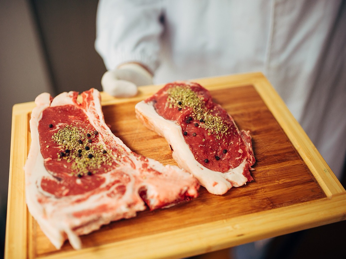 Two seasoned bone-in pork chops on a wooden board